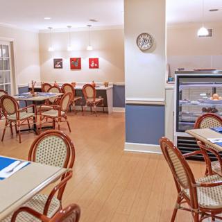 A cozy cafe interior with neatly arranged tables and chairs, featuring subtle lighting and a warm wooden floor.