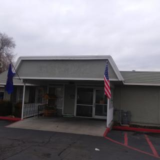 A front view of a building with flags on either side, set against a cloudy sky.