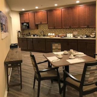 A modern kitchen and dining area with wooden cabinets and a small table set for breakfast.