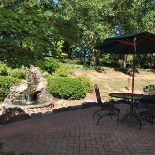 A tranquil garden patio with a seating area and a fountain surrounded by lush greenery.