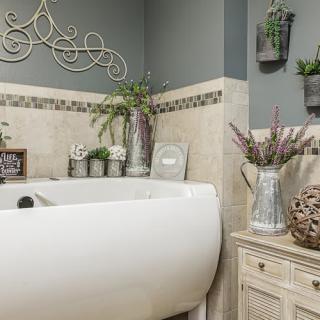 A beautifully decorated bathroom with a white bathtub and various plants in vases.