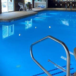 A serene indoor swimming pool with clear blue water and a metal ladder for easy access.