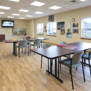 A spacious and well-lit room equipped with tables and chairs, ideal for gatherings or activities.