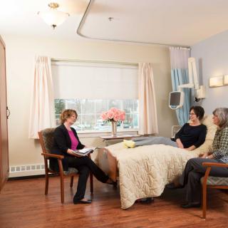 A calm and welcoming hospital room with visitors seated near a bed.