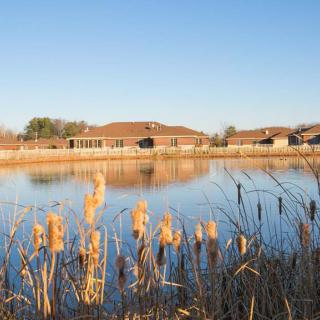 Houses reflected in a tranquil lake surrounded by reeds.