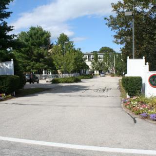 A peaceful entrance to a community lined with trees and flowers.