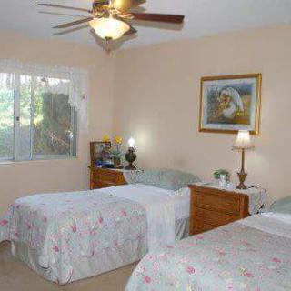 A cozy bedroom with twin beds, a ceiling fan, and warm lighting.