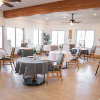 A bright, empty dining room with neatly arranged tables and chairs.