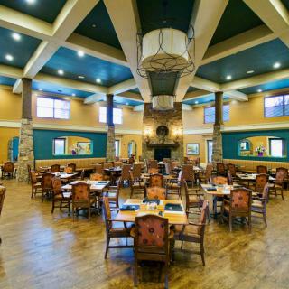 Spacious dining area with multiple tables and chairs, designed with high ceilings and warm lighting.