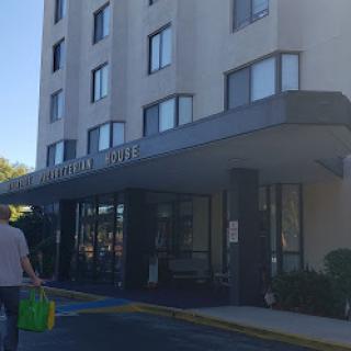 A person walking towards the entrance of a hotel on a sunny day.