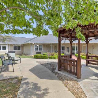 A peaceful courtyard with a wooden gazebo and benches under a tree.