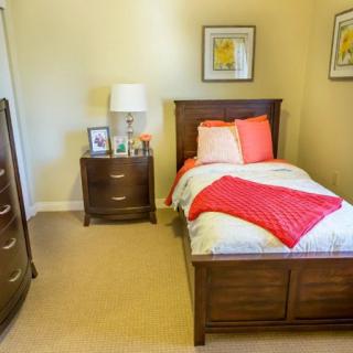 A cozy bedroom with a single bed, wooden furniture, and decorative elements.