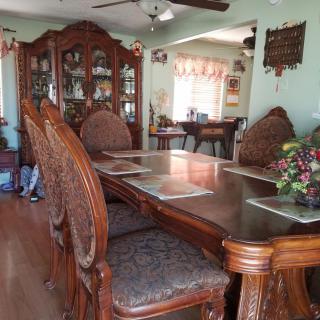 A dining room with a large wooden table and chairs, complemented by a matching cabinet.
