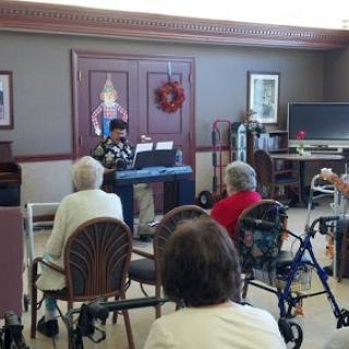 A young performer entertains a group of seniors at a community center.