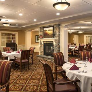 A cozy and elegant dining room with neatly arranged tables and a warm fireplace.