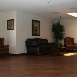 A spacious lobby area with a sofa, armchairs, and wooden flooring.