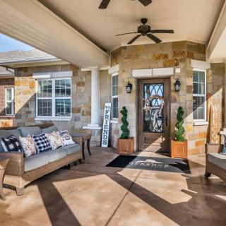 A cozy patio with comfortable outdoor seating, ceiling fan, and stone facade accentuates the relaxing ambiance.