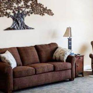 A cozy living room with a brown sofa, wall art, and a side lamp.