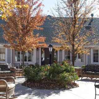 Outdoor seating area surrounded by autumn trees and a building in the background.