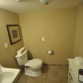A minimalist bathroom featuring a toilet and sink with beige walls and tile flooring.