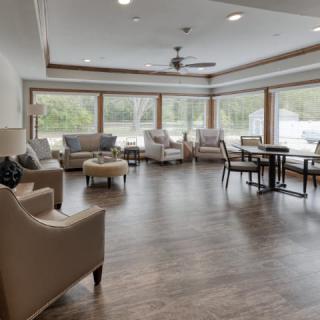 A spacious living room with ample natural light, featuring comfortable seating and wooden flooring.