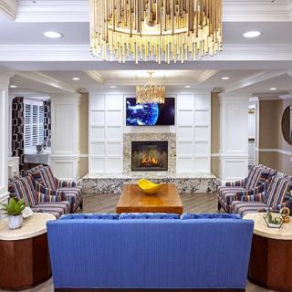 A well-designed living room featuring a blue sofa, fireplace, and elegant chandelier.