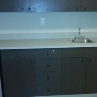 A modern kitchen setup featuring dark cabinetry and a simple sink.
