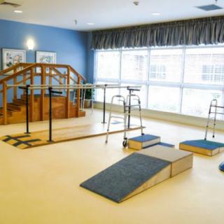 A spacious physical therapy room equipped with rehabilitation tools and exercise ramps.