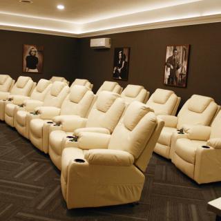 A luxurious home theater with plush recliner seating and movie posters on the walls.