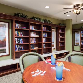 A cozy library space with bookshelves, a table, and chairs, perfect for reading or games.