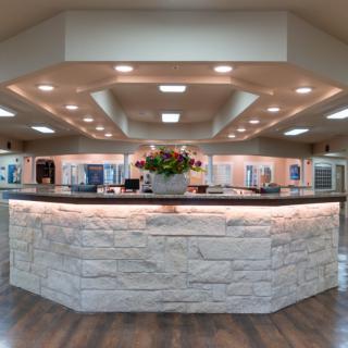 A modern reception area with a stone counter and floral arrangement.