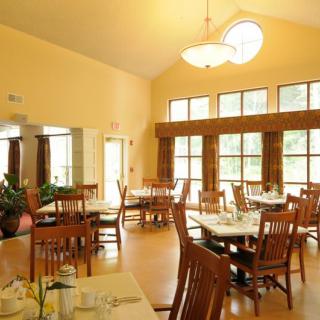 A well-lit dining room with neatly arranged tables and chairs.