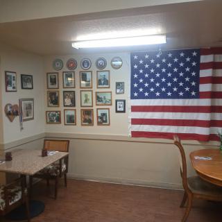 A small dining area with an American flag and various photographs decorating the wall.