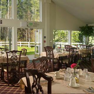 A bright and elegant dining room with large windows offering garden views.