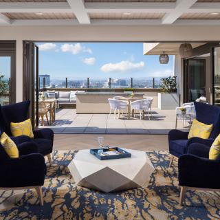 A modern living room opens up to an outdoor patio with a stunning city view.