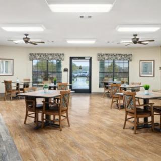 Spacious dining area with wooden flooring and multiple tables and chairs.