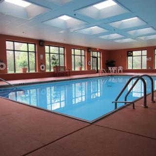A clean and empty indoor swimming pool with large windows and skylights.