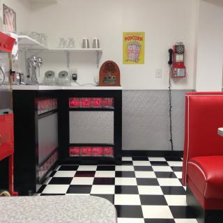 A retro-style diner interior with a classic checkered floor and red booths.