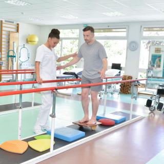 A therapist assists a patient in balance training during a physical therapy session.