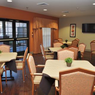 A cozy indoor dining area with neatly arranged tables and chairs, adorned with small green plants.
