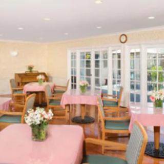 A brightly lit dining area with tables set with pink tablecloths and floral centerpieces.