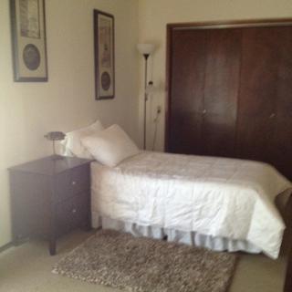A simple bedroom with a single bed, nightstand, and closet.