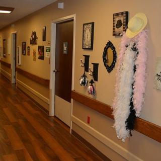 A decorated hallway with framed pictures and a boa draped over a hat.