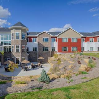 A modern residential building with landscaped surroundings under a clear blue sky.