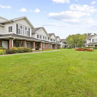 A row of suburban townhouses with a well-maintained lawn in the foreground.