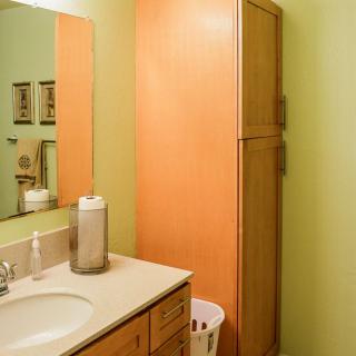 A tidy bathroom with a sink, mirror, and tall cabinet.