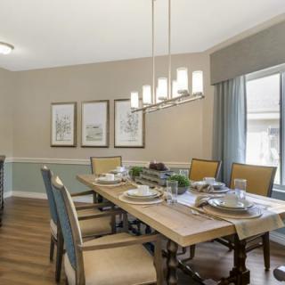 A stylish dining room with a wooden table, cushioned chairs, and elegant lighting.