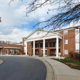 A large brick building with white columns and a curved driveway at the entrance.