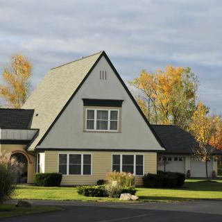 An A-frame suburban house surrounded by autumn foliage.
