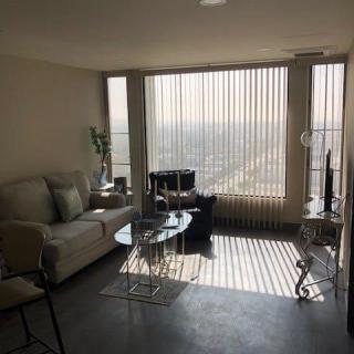 A cozy living room with modern furniture and large windows offering a city view.